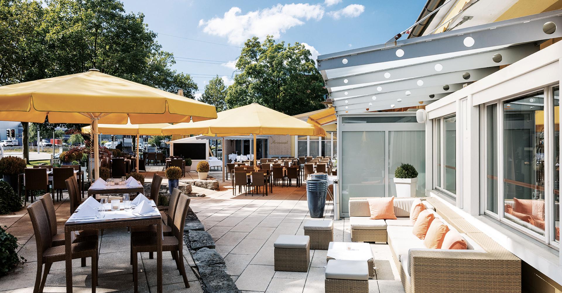 die Terrasse mit Tischen und Schirme im Hotel Sonnental