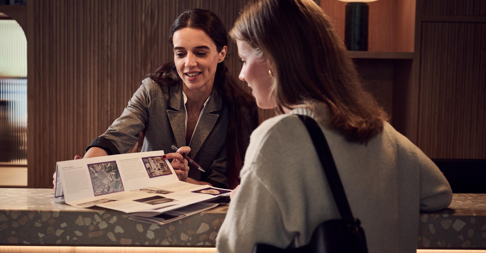 Receptionsmitarbeiterin zeigt einer Kundin eine Karte