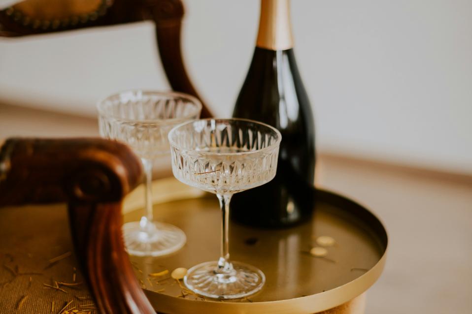 Eine Flasche Champagner steht mit zwei Gläser auf einem Holztisch