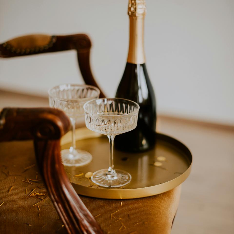 Eine Flasche Champagner steht mit zwei Gläser auf einem Holztisch